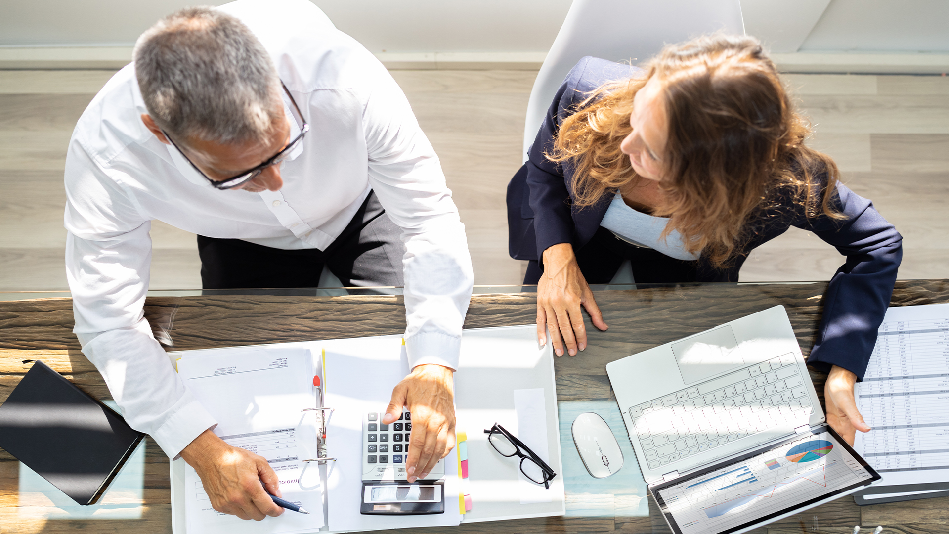 Businesspeople Using Laptop In Office with Calculator