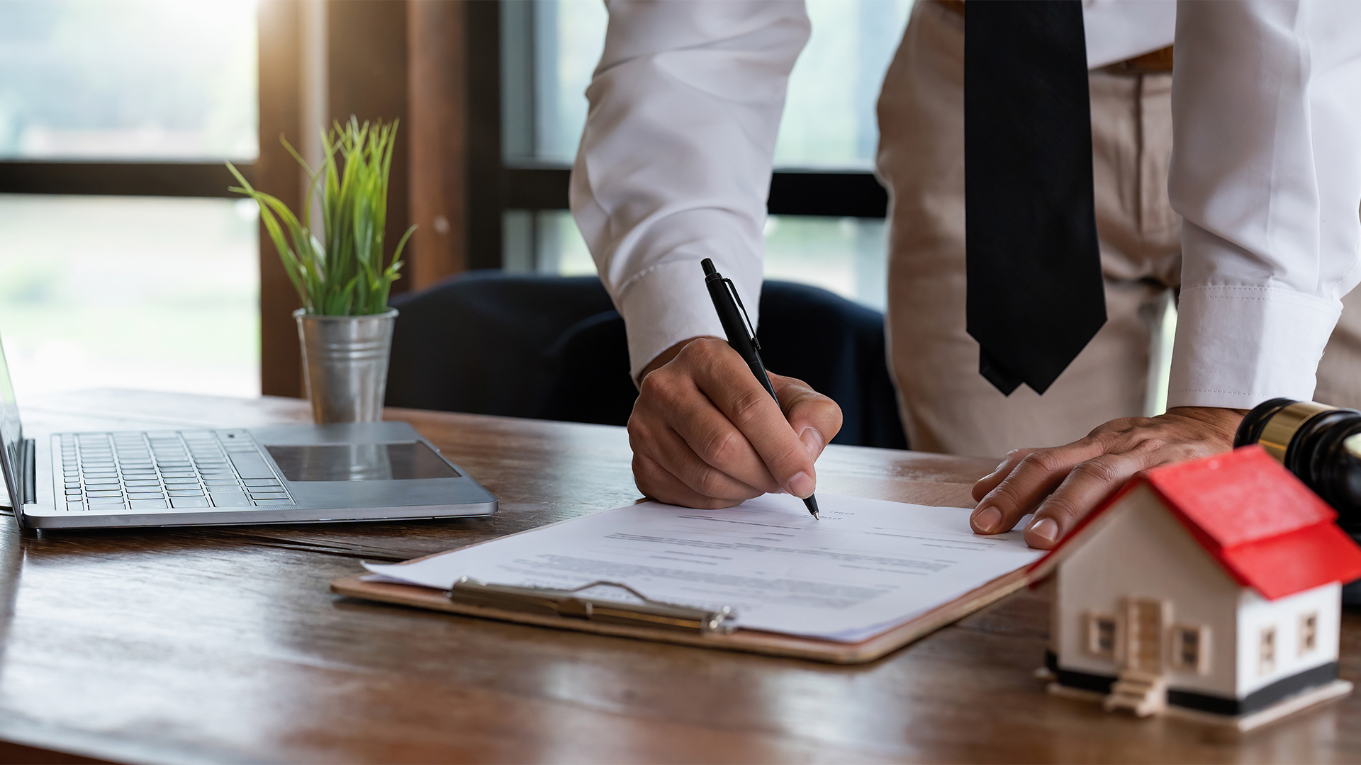 Close up young businessman standing near table with pen in hands, ready signing profitable offer agreement after checking contract terms of conditions, executive manager involved in legal paperwork