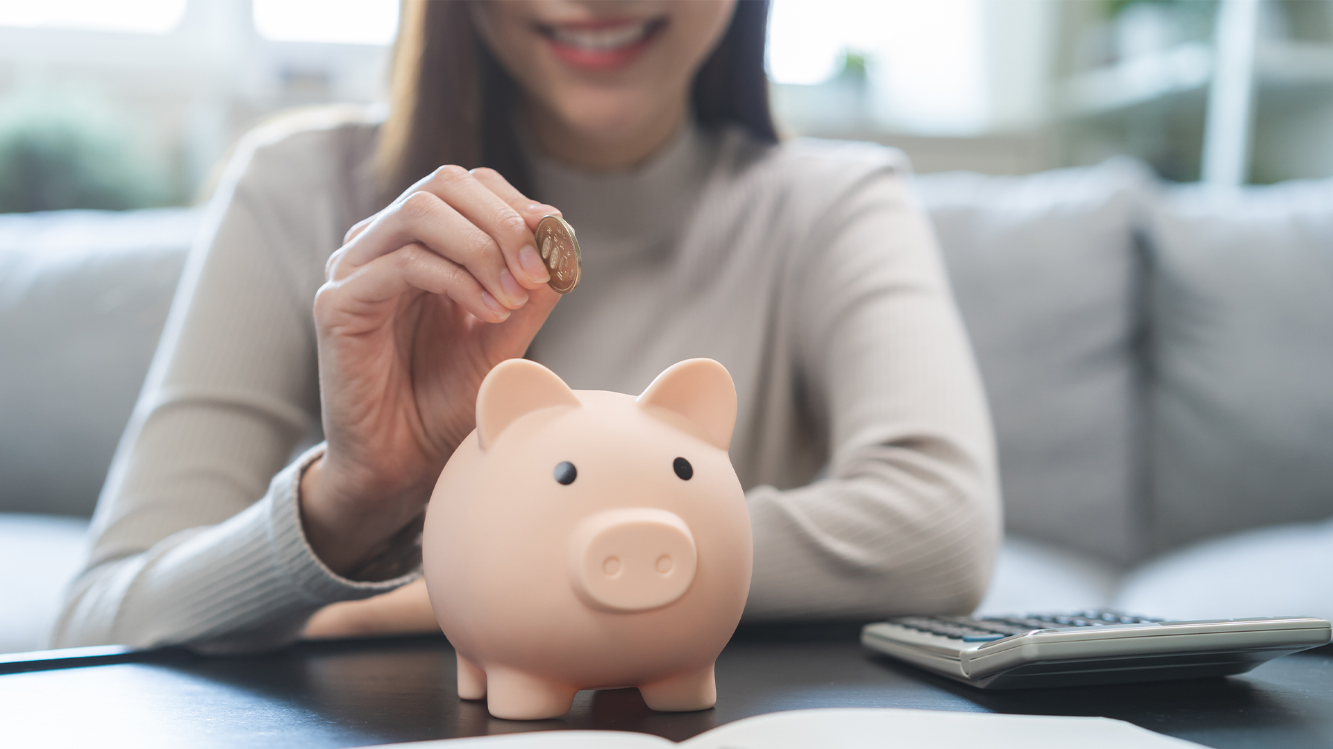 young business woman hand putting coin into piggy for saving cost