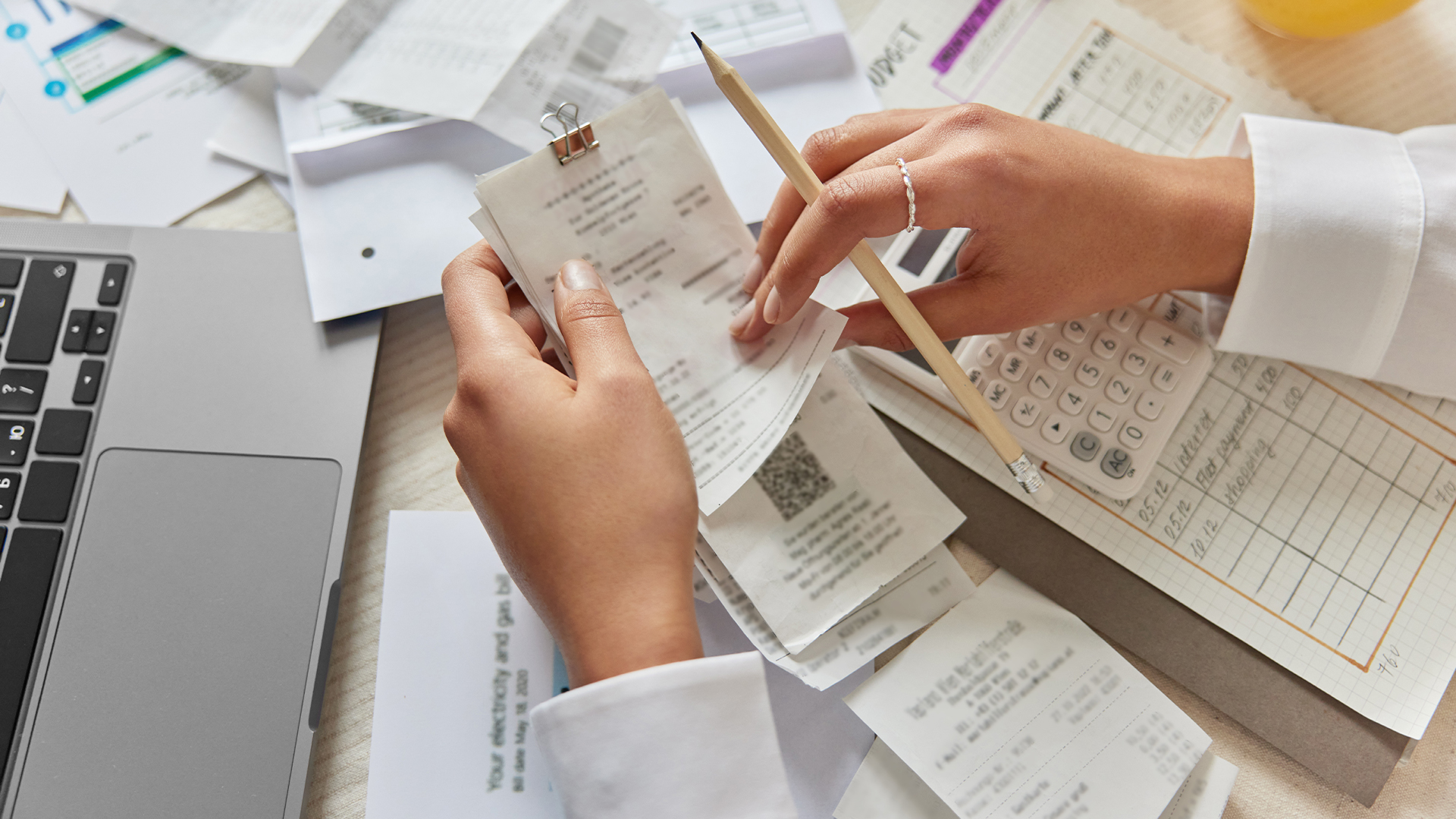 Unrecognizable woman holds receipts pencil uses laptop plans budget