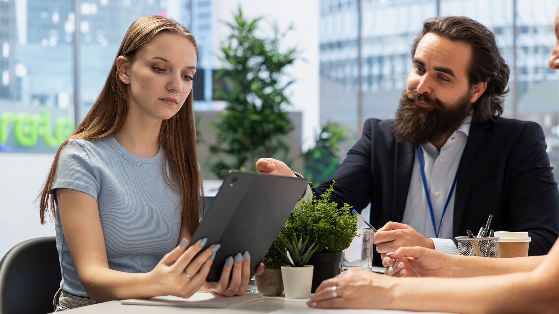 Teenager reading documents on tablet given by student loan advisor in office