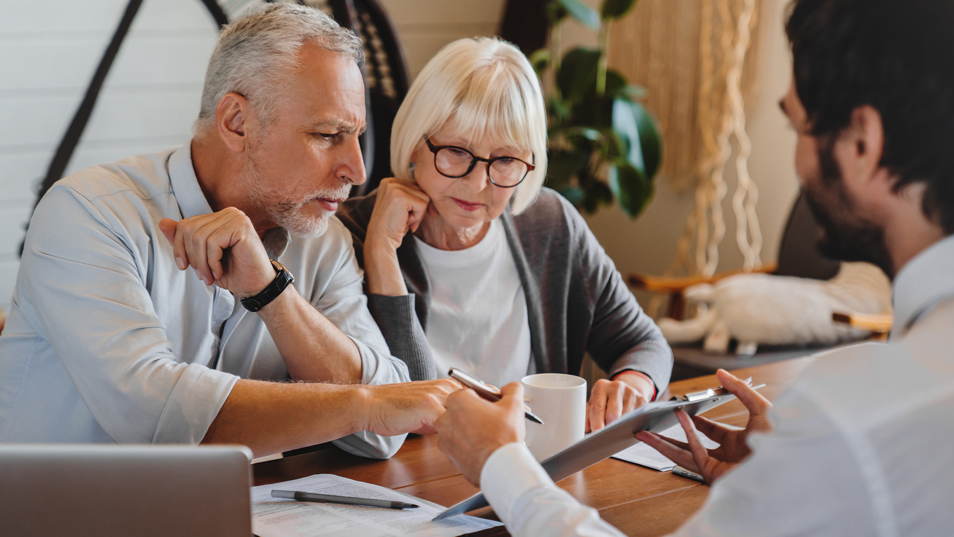 Financial advisor explaining paperwork to elderly retired couple front of desk