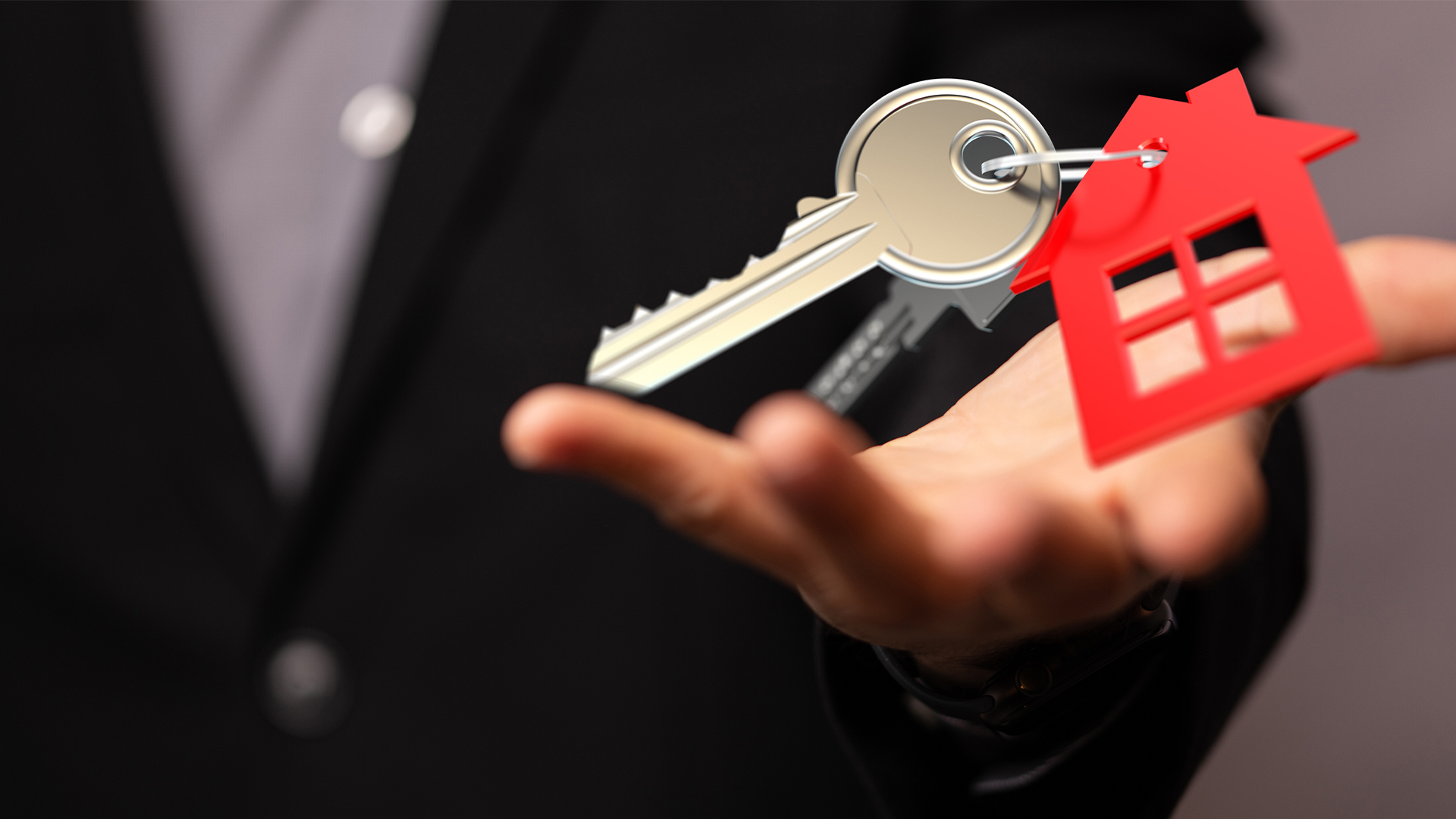 Image of a real estate agent offering house keys, symbolizing homeownership and new beginnings.